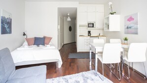 A modern hotel room with a bed, a desk, a chair, a microwave, and a small kitchen area. - 2ndhomes Kluuvi Studios (Helsinki)