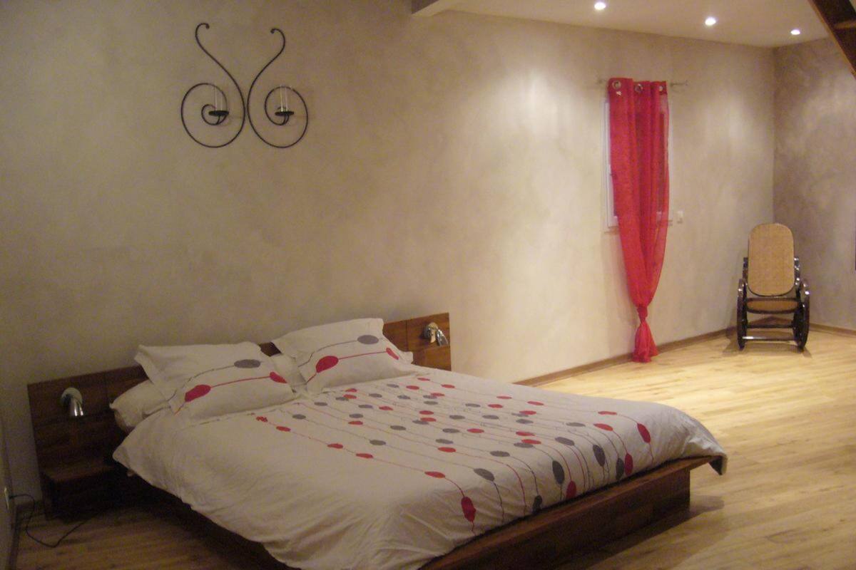 Une chambre à coucher avec un lit en bois, une chaise et un rideau rouge.