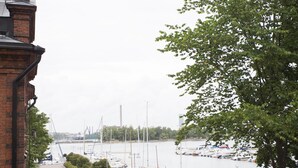Uma marina com barcos atracados, um edifício de tijolos à esquerda e uma árvore em primeiro plano.