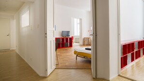 Quarto moderno com cama, televisão e um móvel de armazenamento vermelho.