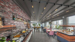 A buffet area with various food options, a brick wall, and a long counter with seating. - Laren Sea Sıde Hotel & Spa (Antalya)
