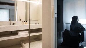 A modern bathroom with a large mirror, a marble countertop, and a glass partition. - Hotel Scenario (Rome)