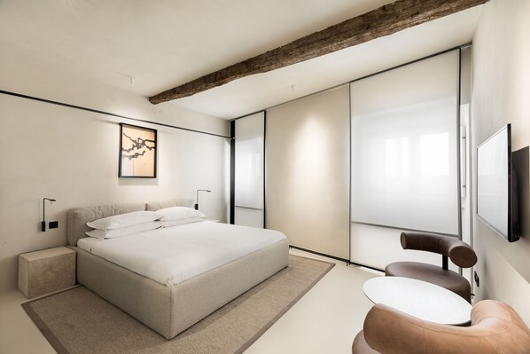A modern bedroom with a large bed, a small table, and a chair. - Hotel Scenario (Rome)