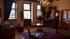 A cozy living room with a fireplace, a chandelier, and a large mirror. - Cape Dutch at Keerweder (Franschhoek)