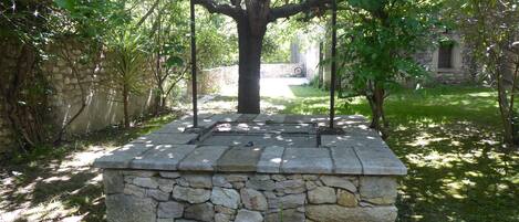 A stone structure with a tree in a garden setting.