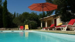 Una piscina con sillas de descanso y una sombrilla.