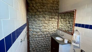 Ein Badezimmer mit Steinwand, Waschbecken, Toilette und einer Pendelleuchte.