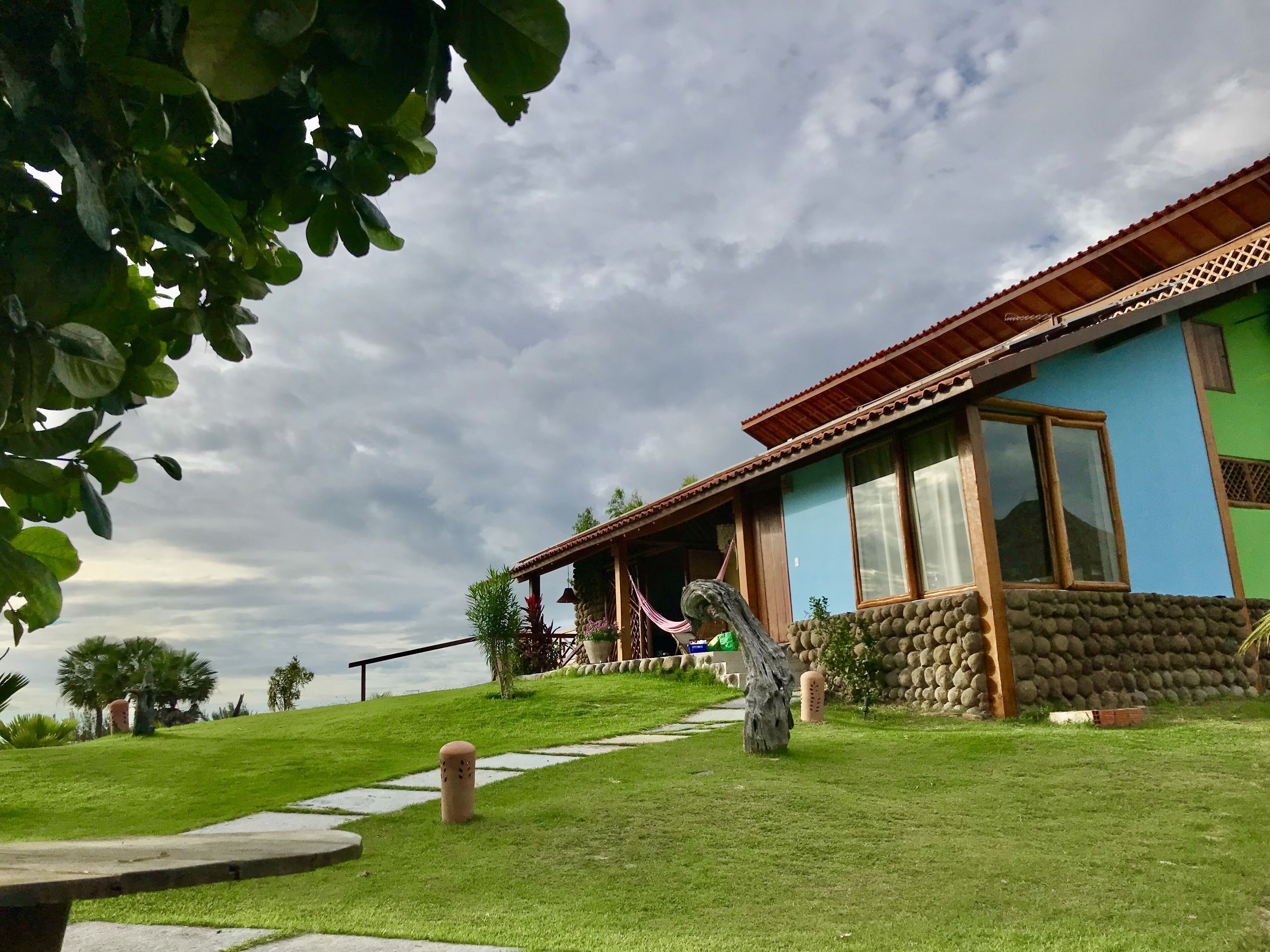 Una casa con pared de piedra, un porche y un camino que lleva a la entrada.