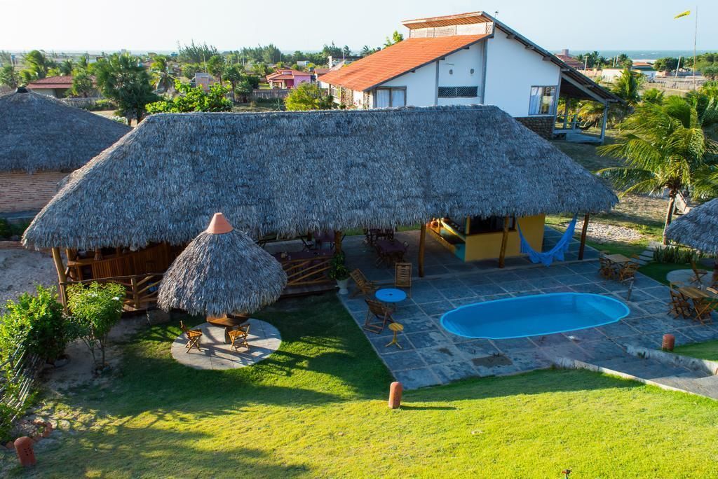 Ein Haus mit einem Strohdach, einem Swimmingpool und einem gepflegten Garten.