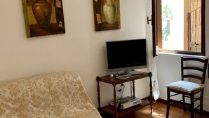 Ett vardagsrum med en soffa, en tv, en fåtölj och två tavlor på väggen.