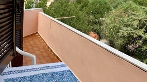 En balkong med utsikt över en by som ligger på en sluttning, ett klinkergolv och en mönstrad matta.