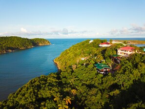 A coastal property with lush greenery, a red-roofed building, and a view of the sea.
