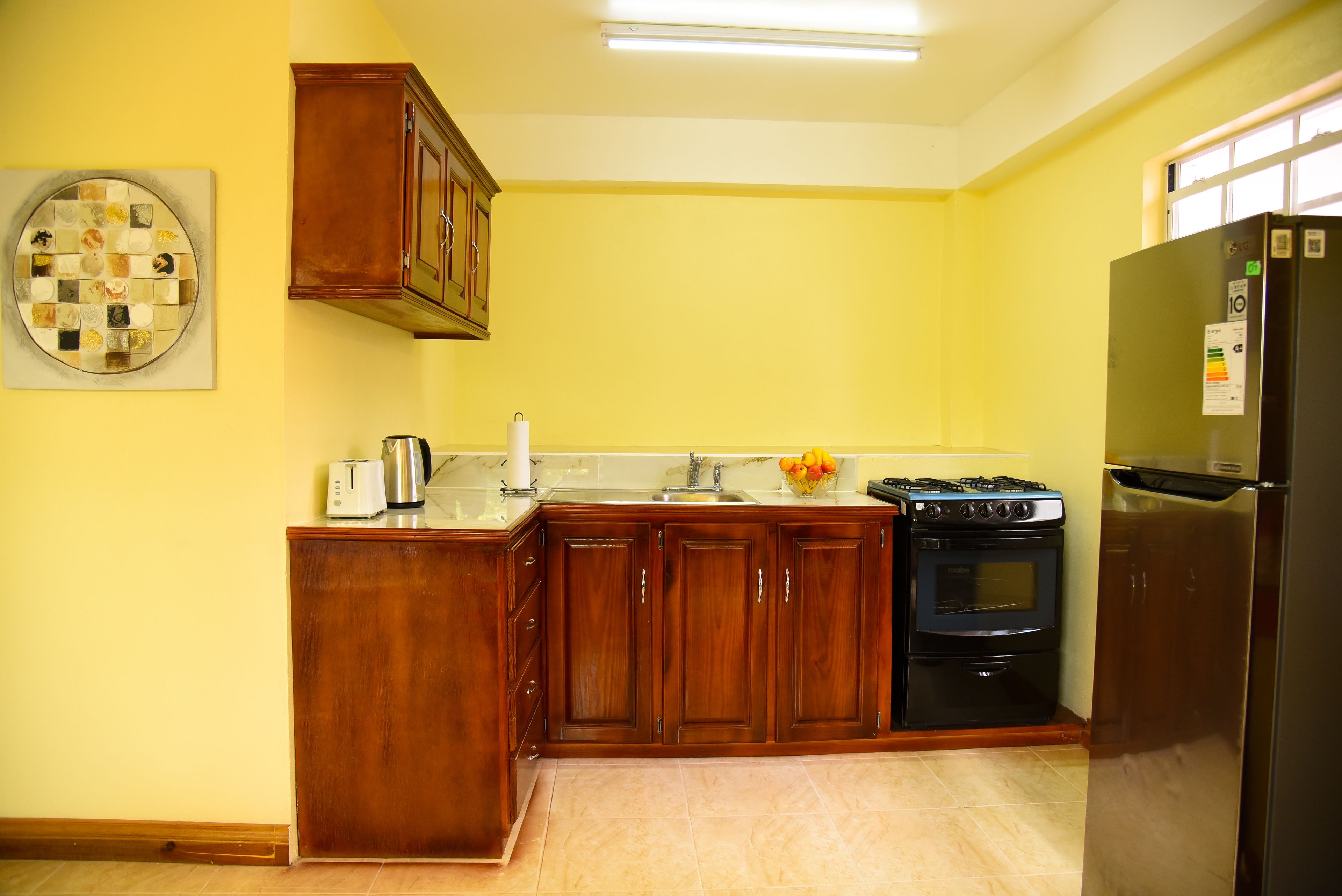 Una cocina con armarios de madera, un refrigerador de acero inoxidable y un horno negro.