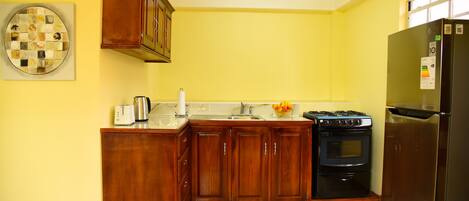 A kitchen with wooden cabinets, a stainless steel refrigerator, and a black oven.