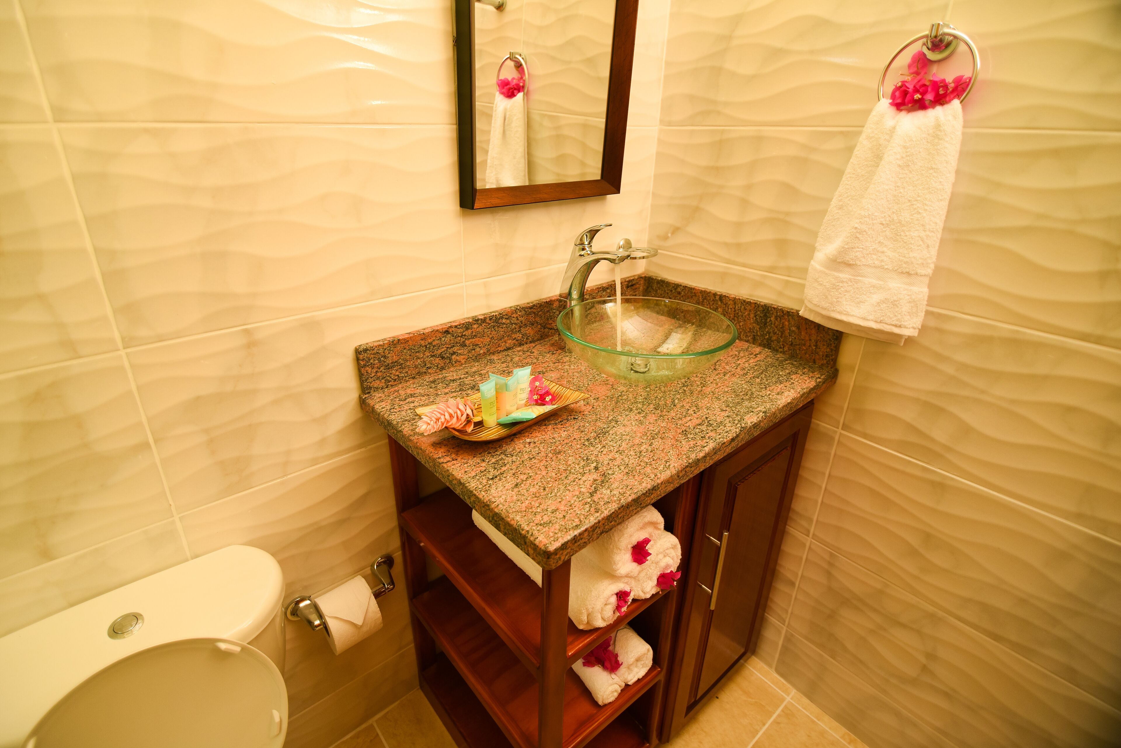 A bathroom with a glass sink, a towel rack with a white towel, and a mirror above the sink.