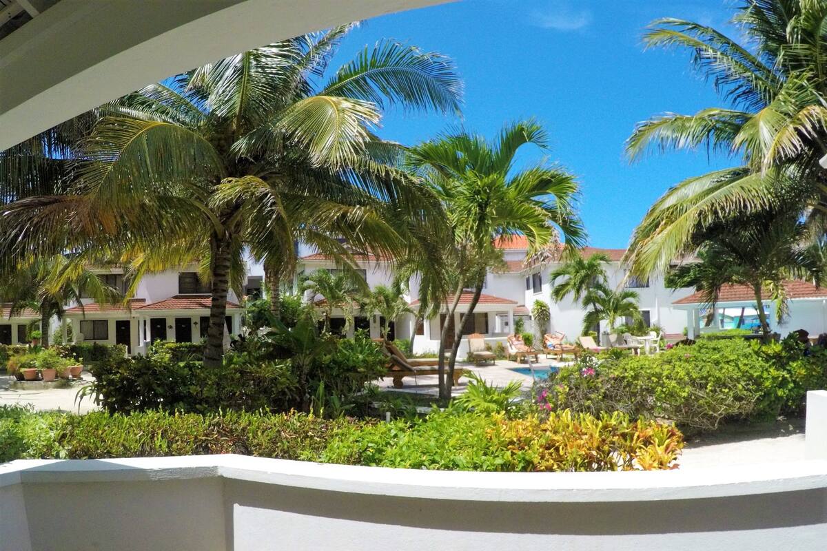Ein Resort mit mehreren weißen Gebäuden, Palmen und einem Poolbereich.