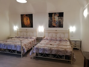 Une chambre à coucher avec deux lits, chacun doté d’une tête de lit et de tables de chevet. Deux appliques murales sont fixées au-dessus de chaque lit.