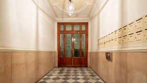 A hallway with a checkered floor, wooden doors, and a row of mailboxes on the right. - Elegant and comfortable apartment near the Duomo. The perfect location. (Firenze)