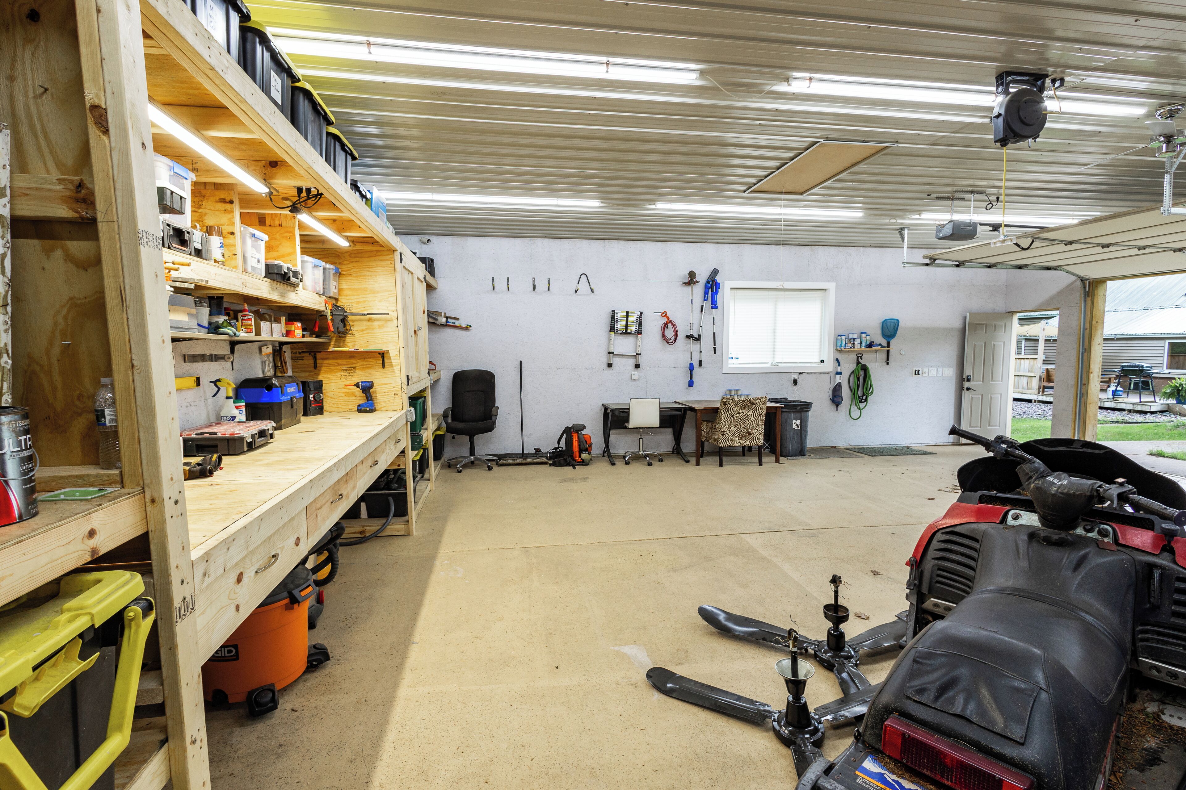 Un atelier équipé d’étagères en bois, d’un établi et de divers outils et équipements.
