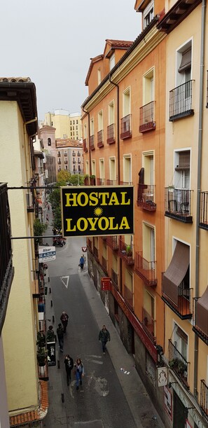 A street view with a sign for 'Hostal Lojola' in a narrow urban alley. - Hostal Loyola - Hostel (Madrid)
