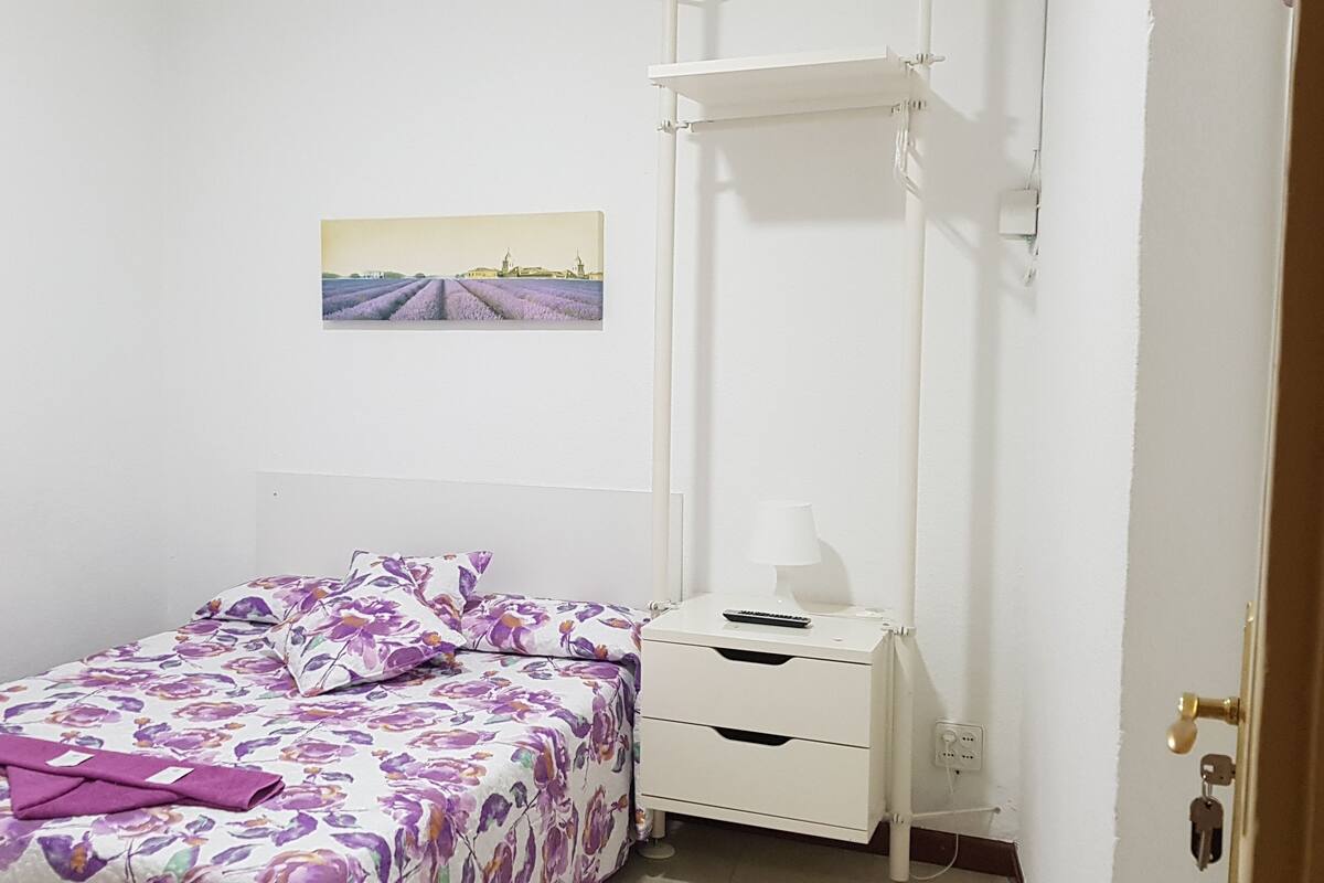 Une chambre à coucher comprenant un lit, une table de chevet, une étagère fixée au mur et deux tableaux encadrés.