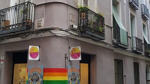 A building with multiple balconies, a rainbow flag, and a sign reading "Hostal Lolo." - Hostal Loyola - Hostel (Madrid)