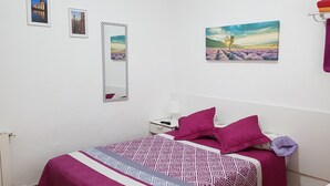 A bedroom with a bed, a nightstand, a mirror, and two framed pictures on the wall. - Hostal Loyola - Hostel (Madrid)