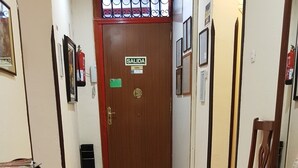 A hallway with a wooden floor, a door labeled 'SALIDA', and a small table with magazines. - Hostal Loyola - Hostel (Madrid)