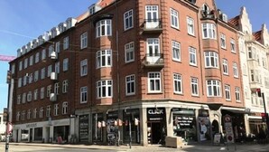 A multi-story building with a corner entrance, featuring a ground-floor shop with a 'CLICK' sign and a 'SHELLOUS' store. - Aalborg City apartments (Aalborg)