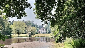 A large building with a symmetrical facade, surrounded by a lake and dense greenery.