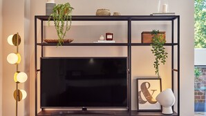 A modern living room with a black TV on a shelf, decorative items, and a floor lamp. - Designer City Centre Apartment (Coventry)