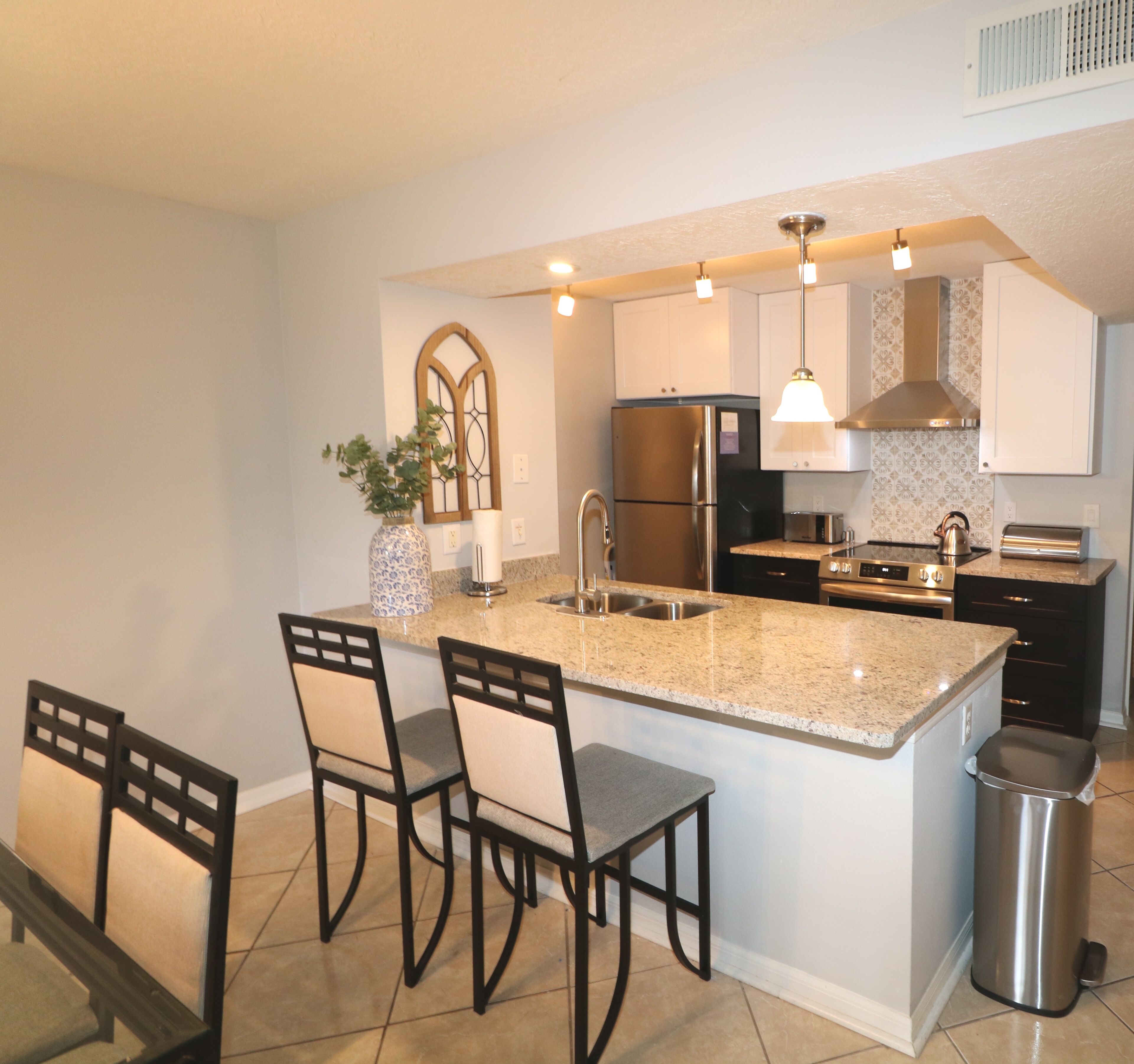A modern kitchen with a central island, stainless steel appliances, and pendant lighting.