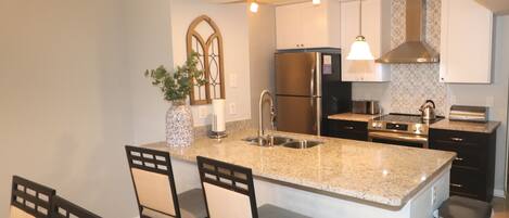 A modern kitchen with a central island, stainless steel appliances, and pendant lighting.