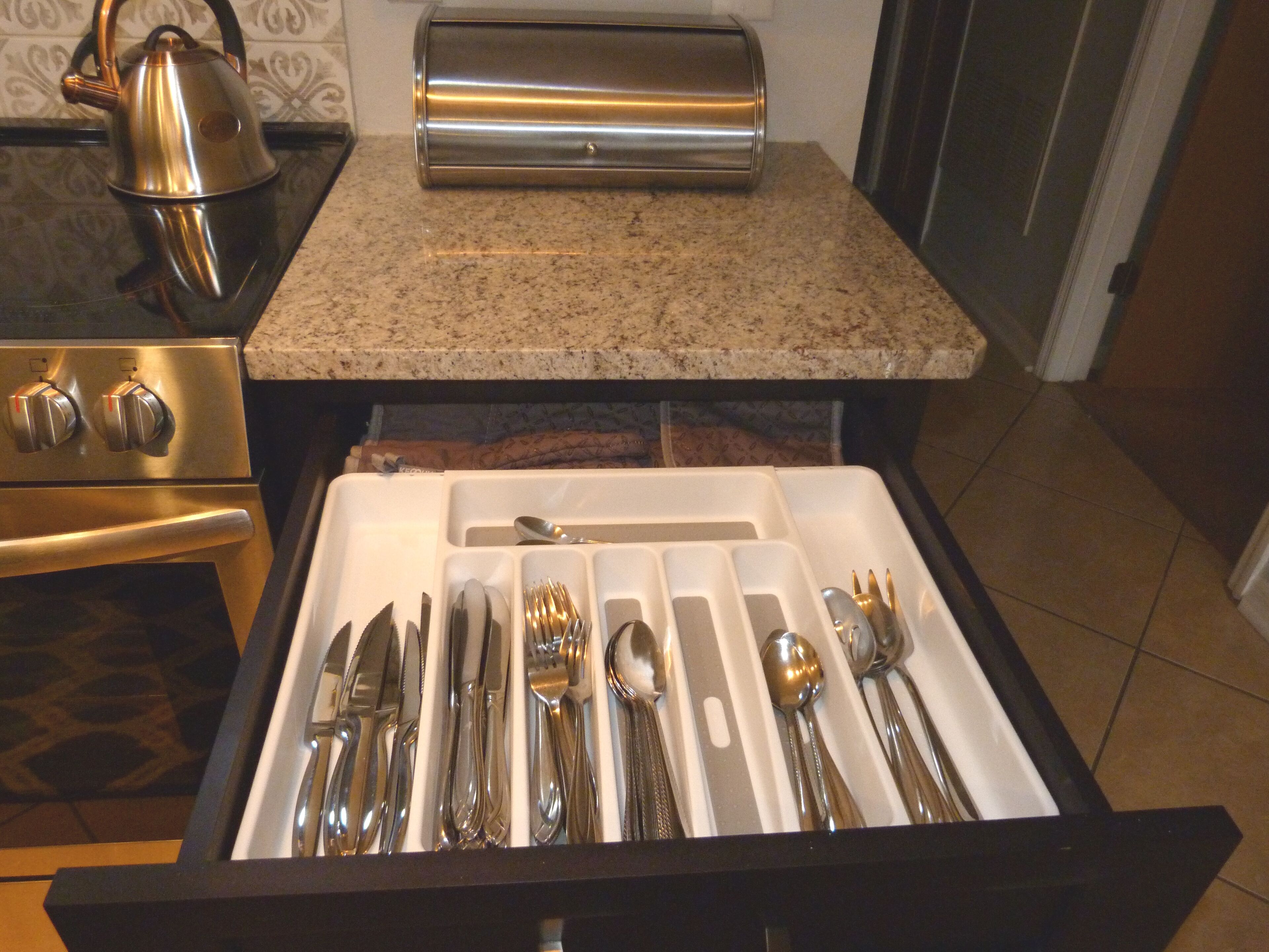 A kitchen drawer with utensils and a toaster.