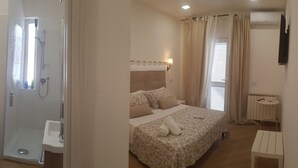 A hotel room with a shower, toilet, bed, bedside table, and an air conditioning unit. - Il Fiore di Loto (San Felice Circeo)