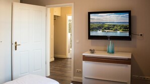 A hotel room with a bed, a TV mounted on the wall, and a view of a lake through the window. - Autorenhaus Franz Kafka (Heringsdorf)