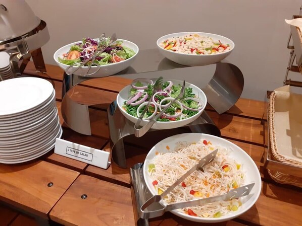 A buffet table with various salads and a sign indicating '5 TYPE OF SALAD'.