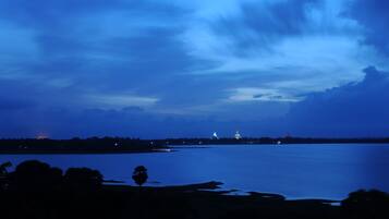 A nighttime view of a large body of water with a distant illuminated structure, likely a government building, and a lighthouse.