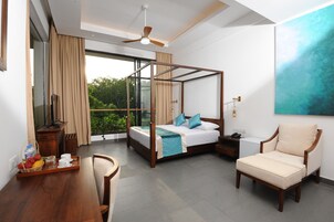 Un dormitorio moderno con cama con dosel, un escritorio de madera con bandeja de fruta, una silla y un ventanal con vistas a zonas verdes.