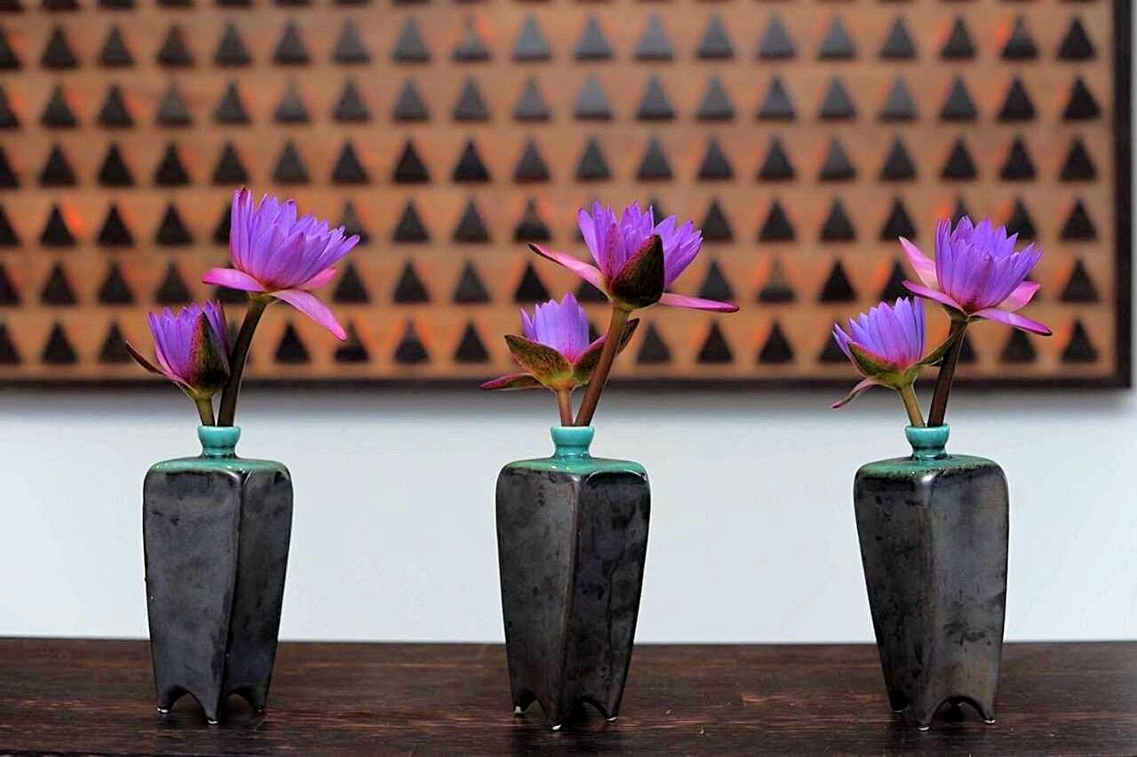 Trois vases carrés ornés de fleurs violettes, posés sur une surface en bois.