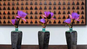 Três vasos quadrados com flores roxas sobre uma superfície de madeira.