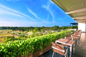 Una terraza con mesas y sillas que da a un paisaje verde y exuberante.