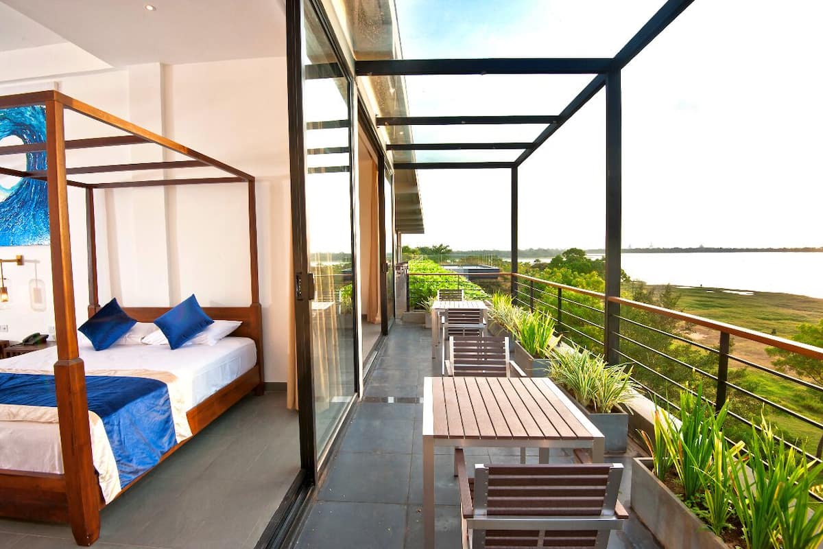 Ein Balkon mit einem Bett und einer Sitzecke mit Blick auf ein Gewässer.