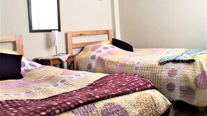 A bedroom with two single beds, a bedside table with a lamp, and a wall-mounted mirror. - Huancaro Familiar Apart (Cusco)