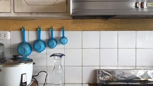 A kitchen with white cabinets, a stove, and blue measuring spoons hanging on the wall. - Huancaro Familiar Apart (Cusco)