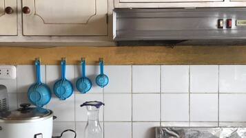 Una cocina con armarios blancos, una estufa y cucharas medidoras azules colgadas en la pared.