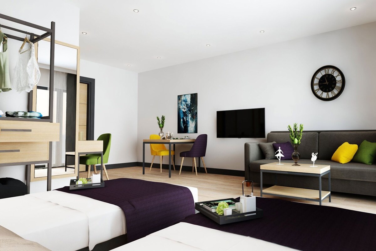 Una sala de estar moderna con un sofá, una mesa de centro, un televisor, un escritorio con una silla y una cama.