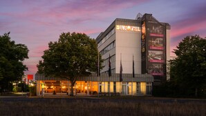 A modern hotel with a prominent 'DIVOTEL' sign, large windows, and a well-lit entrance. -  DIWOTEL by Trip Inn Frankfurt Airport Dreieich (Dreieich)