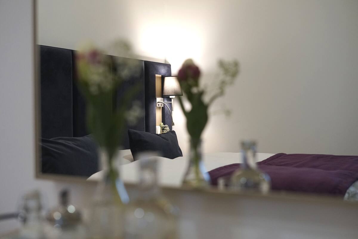 Une chambre à coucher avec un lit, une table de chevet, une lampe et un miroir.