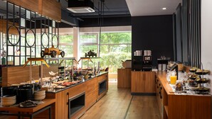 A modern kitchen with wooden cabinets, a central island, and a large window offering a view of greenery. -  DIWOTEL by Trip Inn Frankfurt Airport Dreieich (Dreieich)